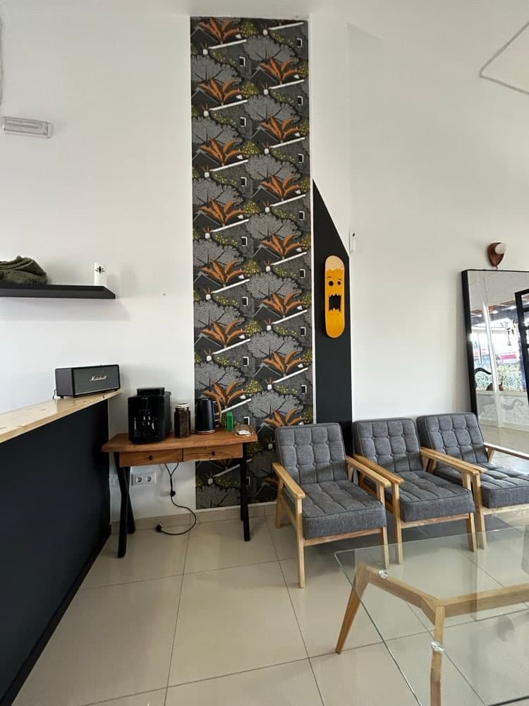 The waiting corner, with grey armchairs, a coffee table and a patterned wall panel.