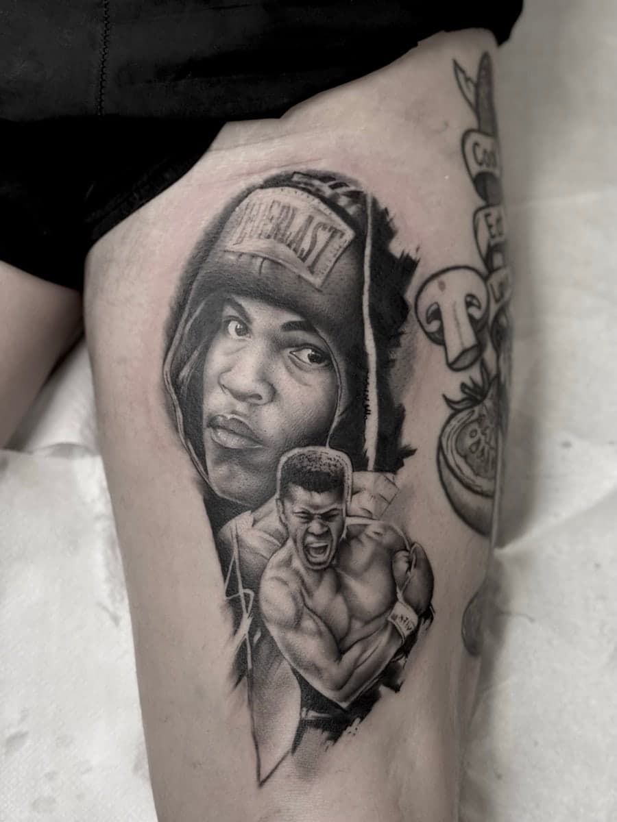 Black and grey portrait of a boxer in a hooded robe, with a fighter mid-punch below, on the thigh.